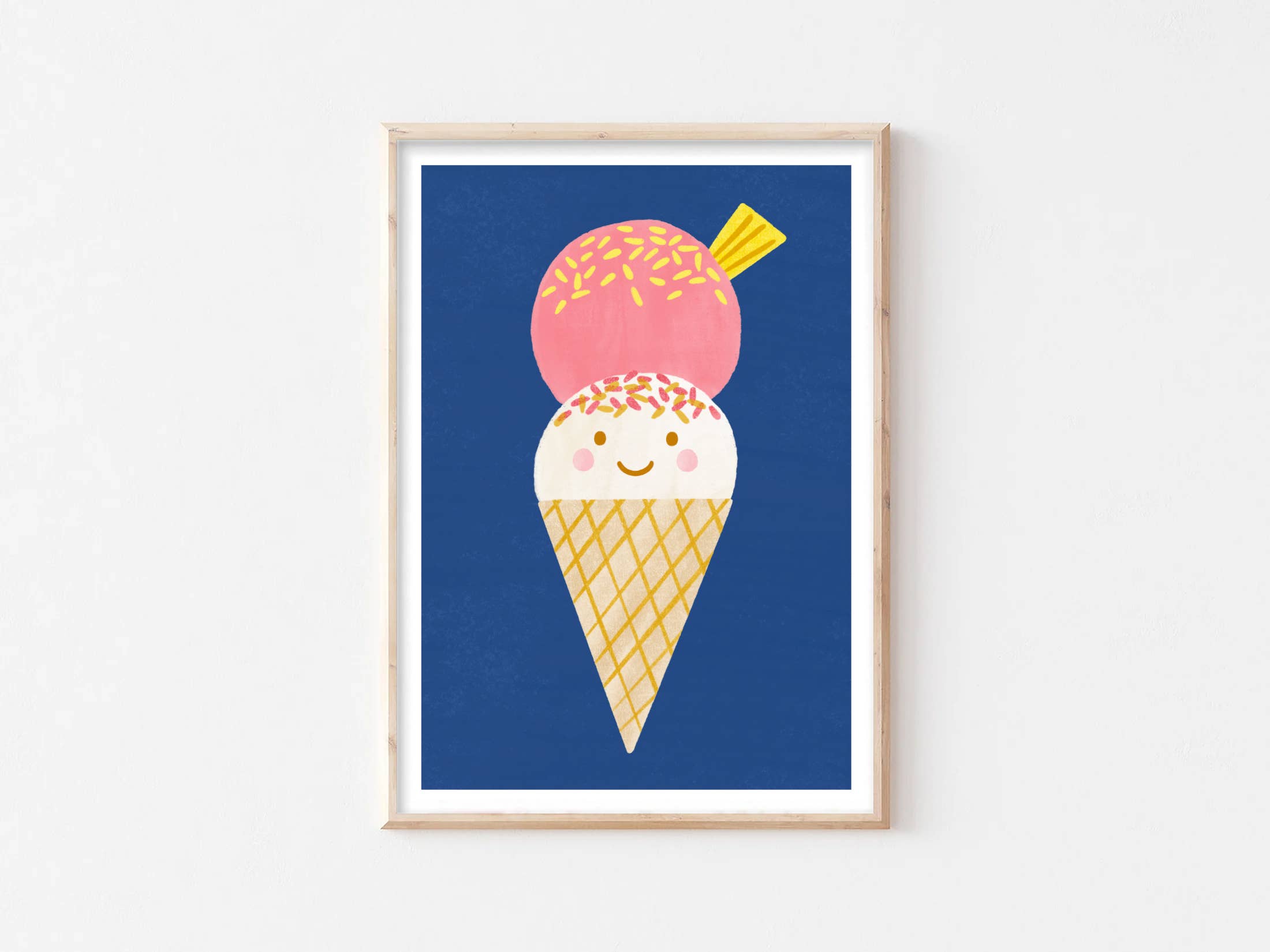 Introducing the Ice Cream Wall Art Print by LAUREN SISSONS STUDIO: a delightful framed artwork featuring an adorable ice cream cone illustration. The cone boasts a cheerful face and two delectable scoops of ice cream—one white with orange sprinkles and one pink with multicolored sprinkles. Printed on high-quality art paper, this contemporary piece stands out brilliantly against its solid blue background.