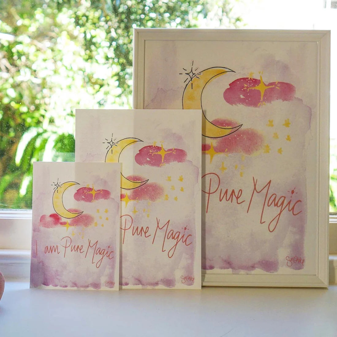 Discover the "I am Pure Magic Art Print A4 (Unframed)" by SUN CHILD, featuring a stunning hand-painted watercolor illustration. This print showcases three art pieces adorned with a crescent moon, pink clouds, and yellow stars. The elegant "Pure Magic" text is scripted against the backdrop of a blurred green garden view—crafted to inspire and captivate any viewer.