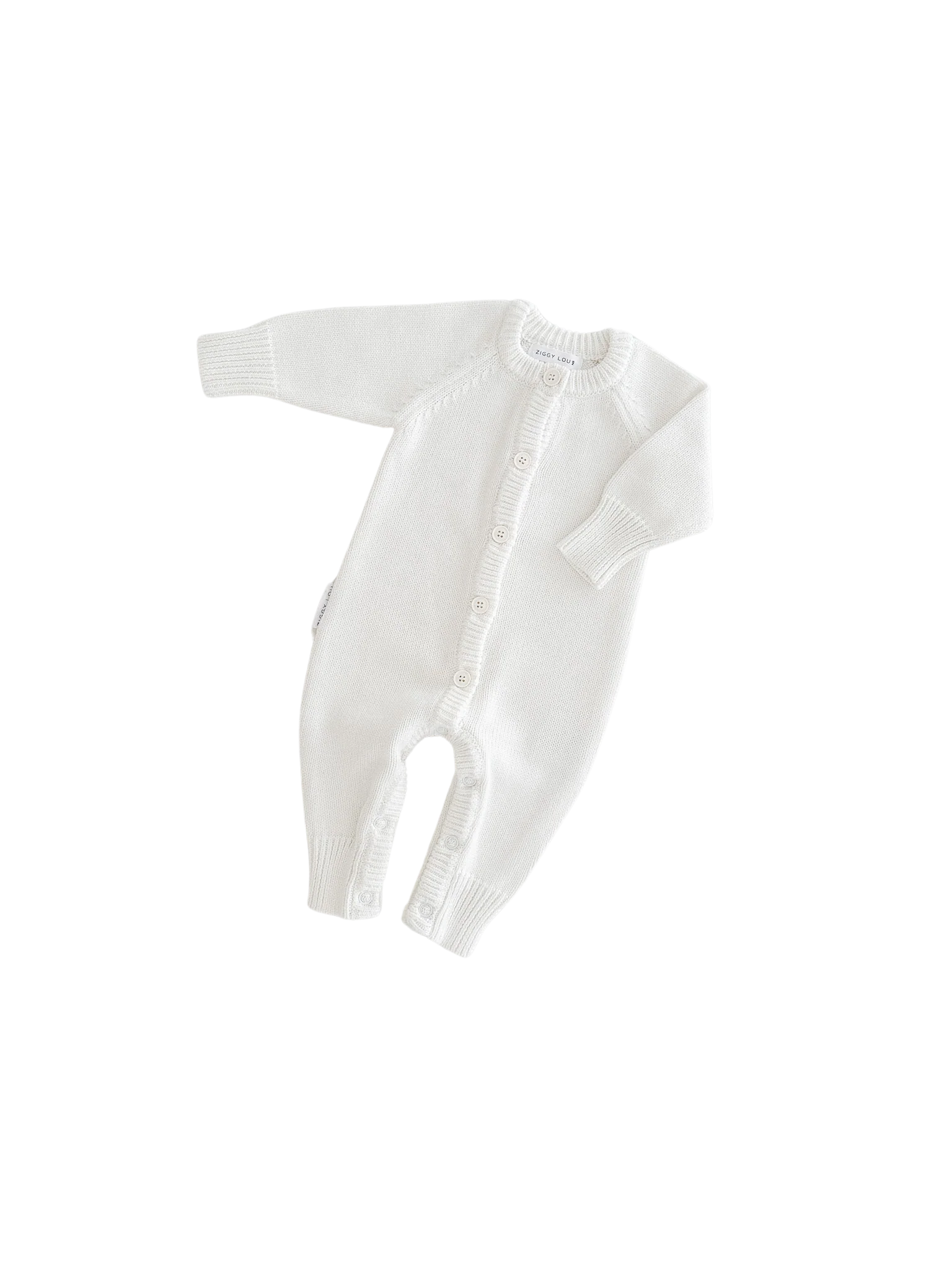The Ziggy Lou - Classic Knit Romper Milk by ZIGGY LOU is a long-sleeved, white knitted romper with front and leg buttons, perfect for keeping your little one cozy during winter.