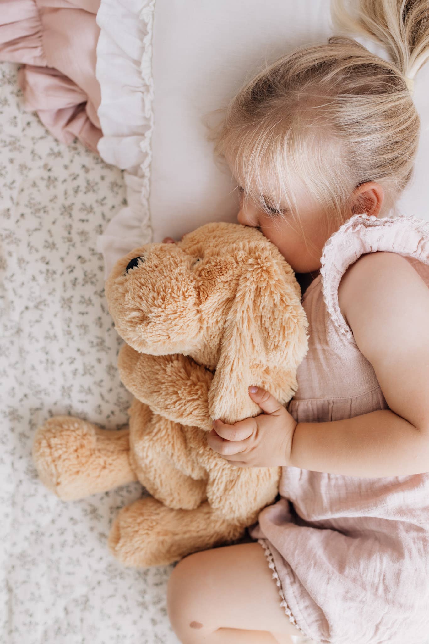 A young girl holding a weighted puppy dog toy in bed.