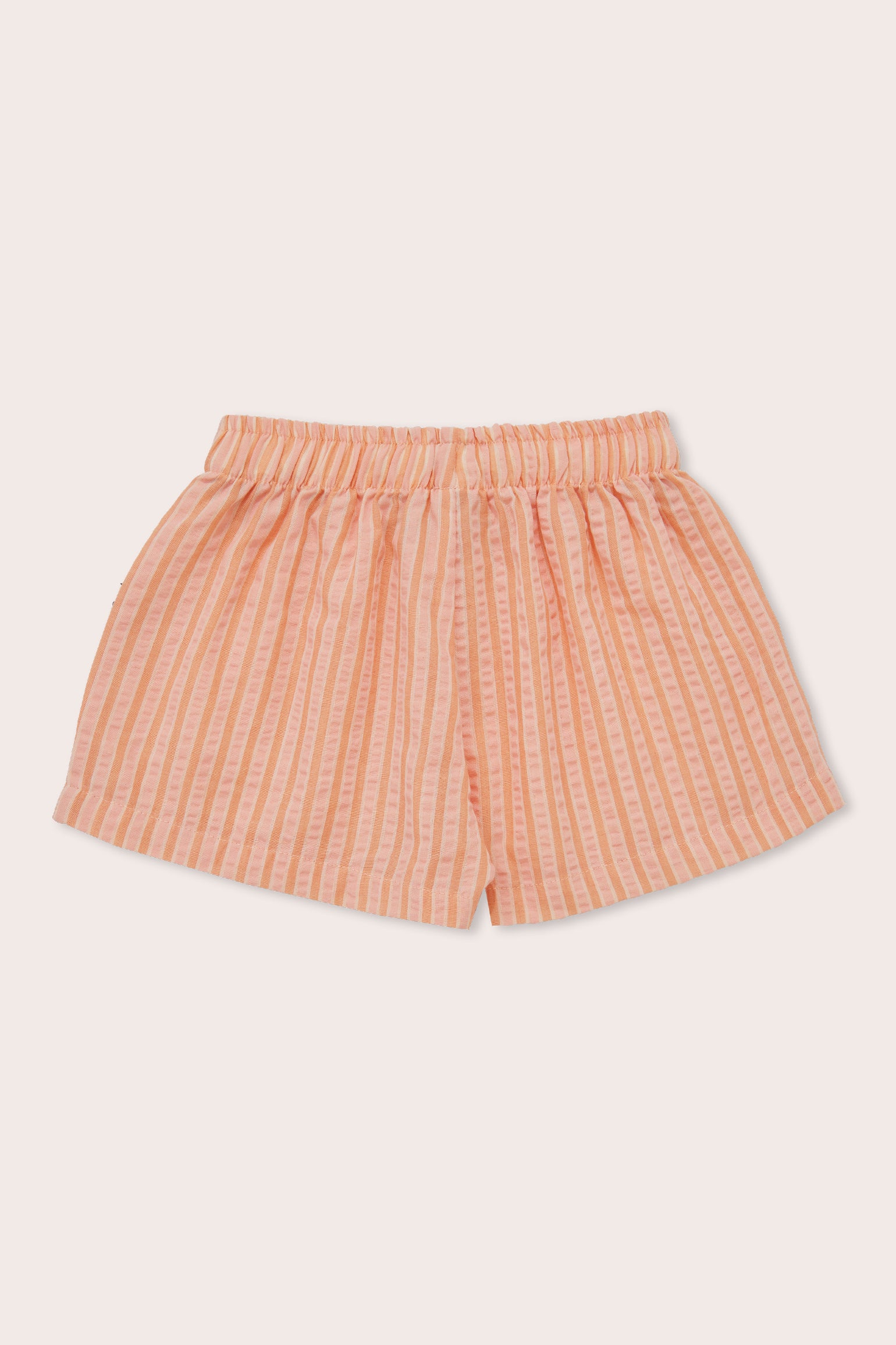 The Cantaloupe Wide Shorts by OLIVE + THE CAPTAIN are peach-colored with vertical striped patterns. These mid-thigh length shorts feature an elastic waistband for a comfortable fit. Crafted from a premium cotton polyester blend, the design is simple and casual, perfect for everyday wear against a plain off-white background.