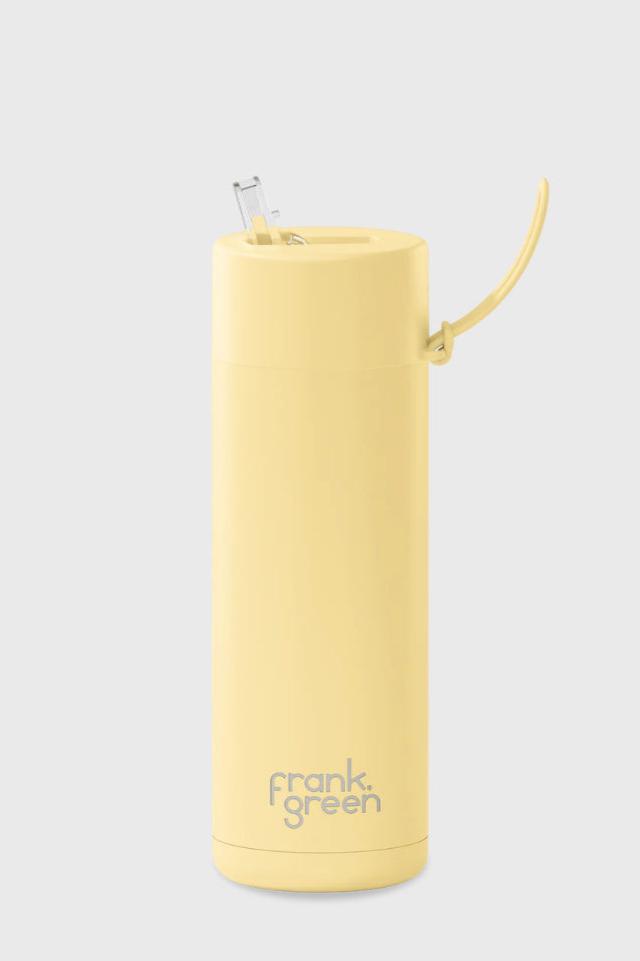 A tall, cylindrical Frank Green Ceramic Reusable Bottle with a 595ml (20oz) capacity, featuring a Buttermilk yellow color and "FRANK GREEN" written on the bottom. Made from durable stainless steel and vacuum insulated, it keeps your drinks at the perfect temperature. The bottle comes with a flip-up straw lid and handle. The background is plain grey.