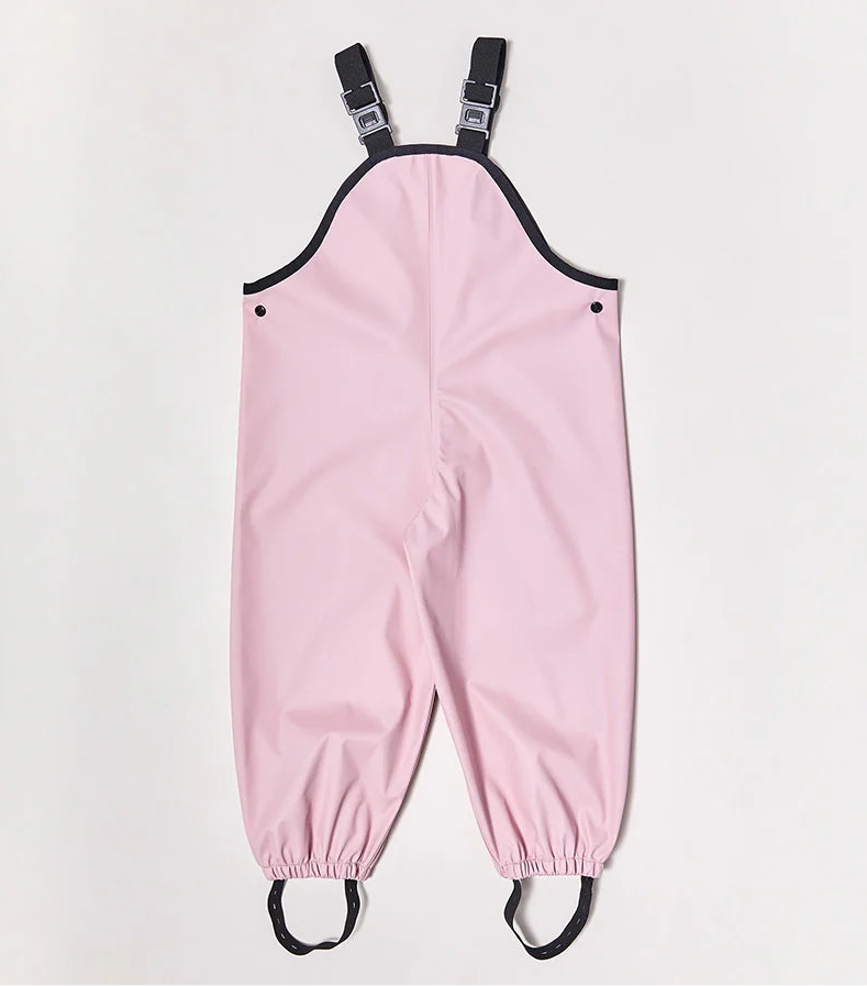 Rainkoat ~ Waterproof Overalls Blush by RAINKOAT: Pink children's waterproof overalls with black adjustable straps, elastic cuffs and foot loops, heat-sealed seams, and black trim on a white background.