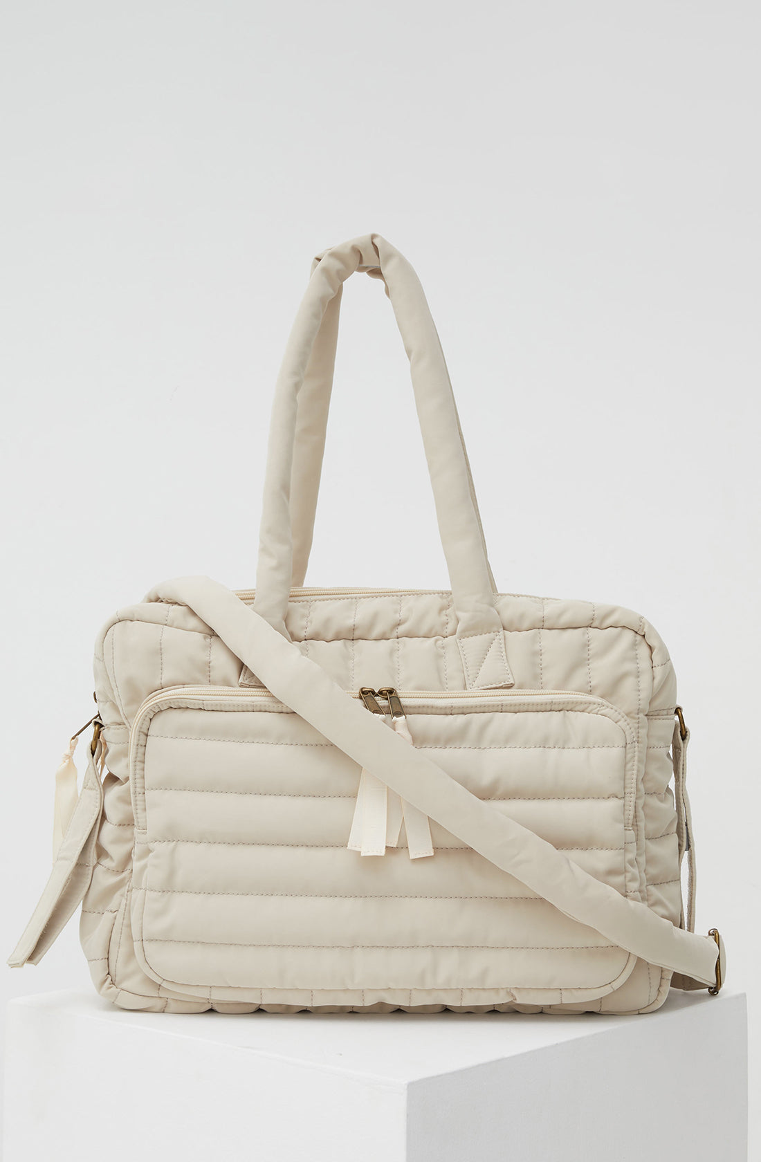 PHILÉ baby bag in cream with strap across the front.