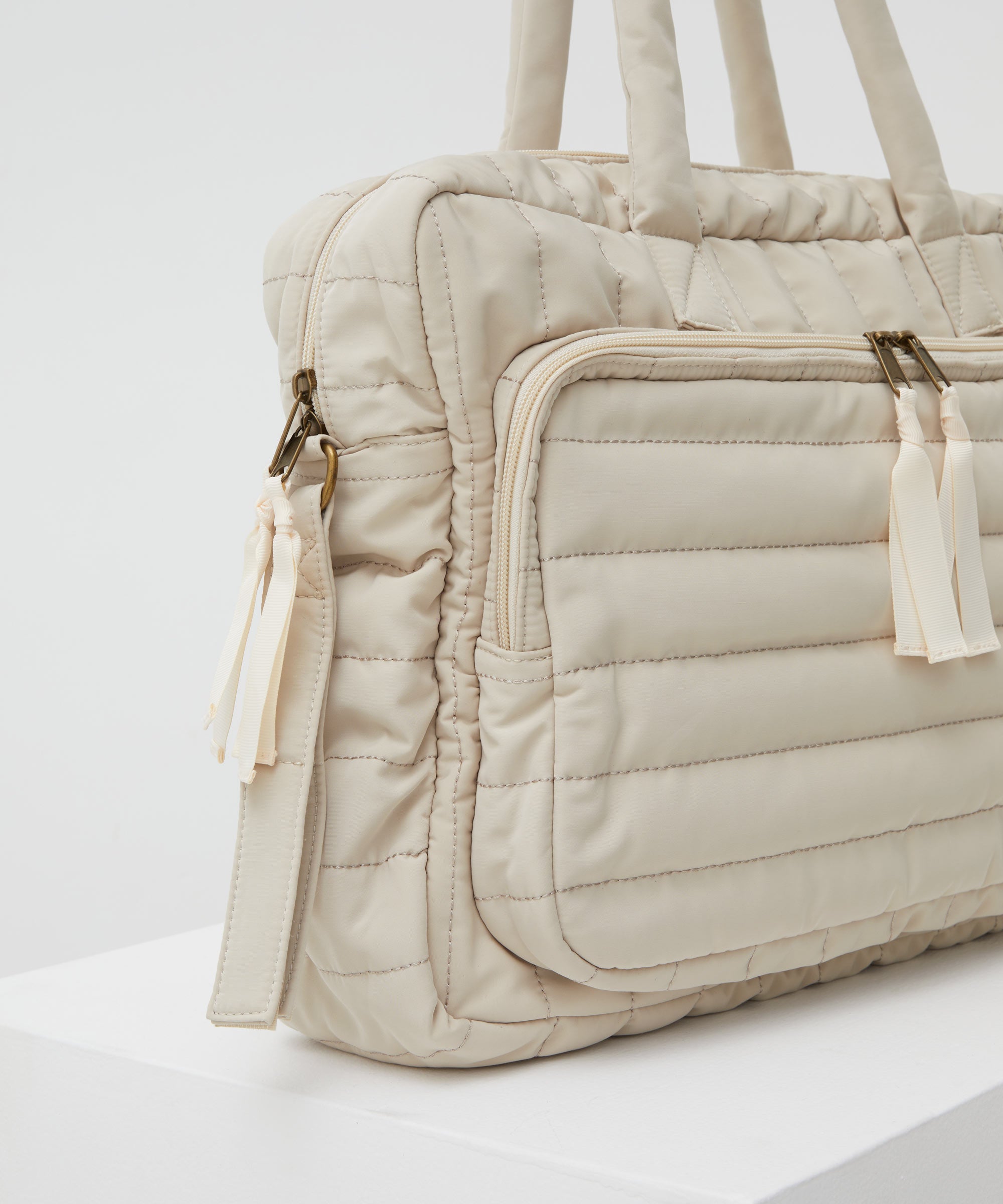 Close up of the PHILÉ baby bag in cream from a side 45 degree angle.