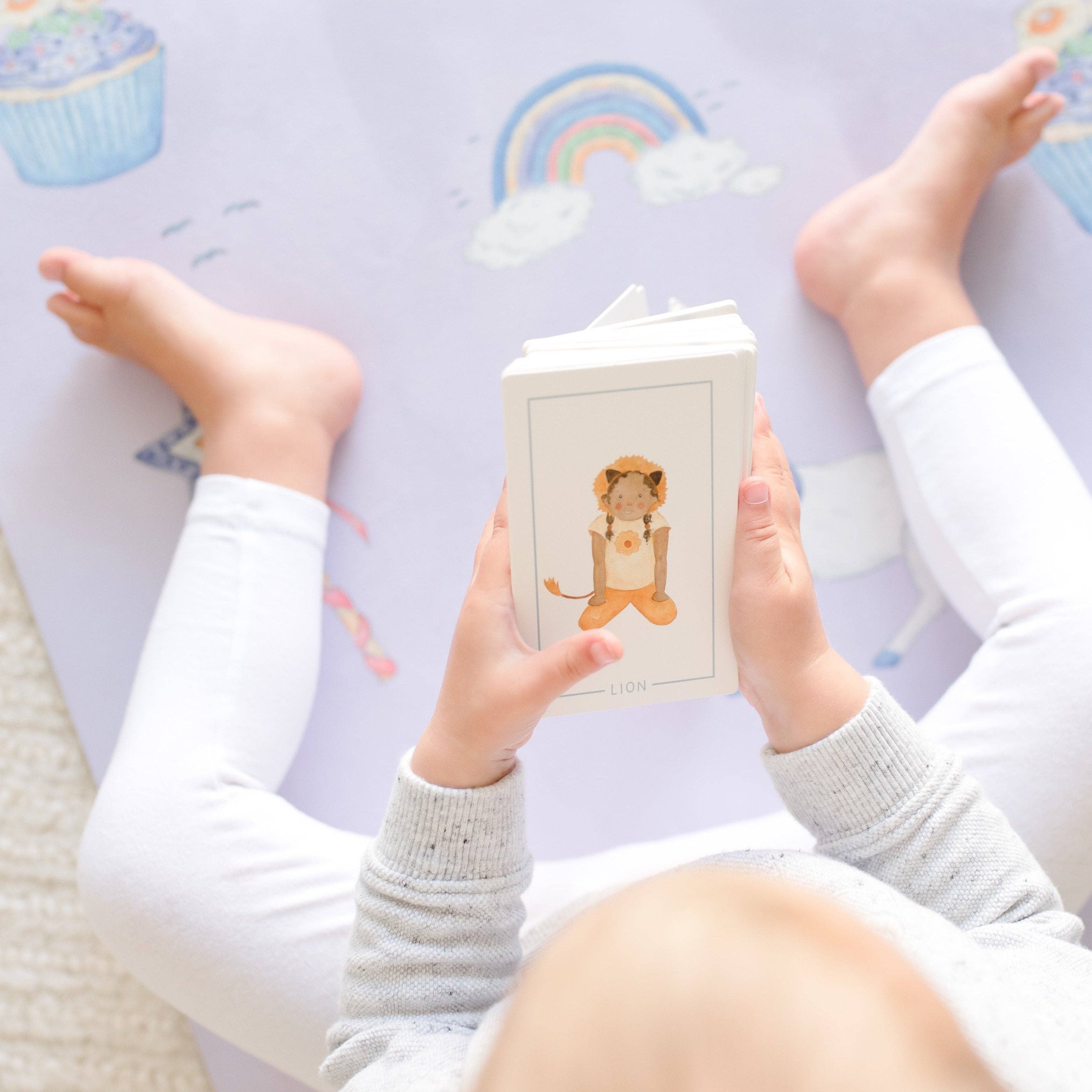 A young kid holding cards in their hands while sitting on a light blue yoga mat.