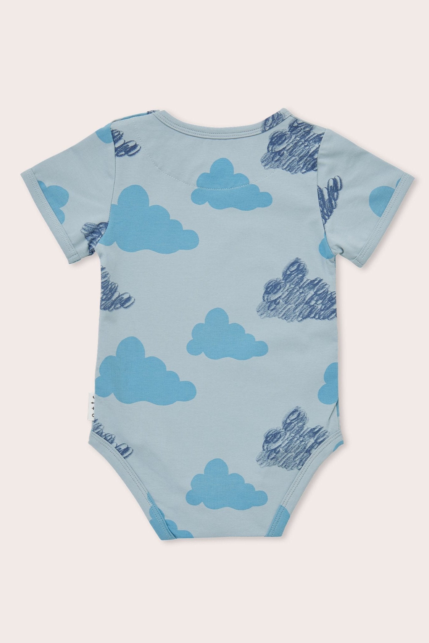 The OLIVE + THE CAPTAIN Clouds Bodysuit is a light blue baby onesie with short sleeves, featuring a playful crayon clouds print in dark and light shades of blue. Made from premium cotton, the garment has a round neckline and is designed for ease and comfort.