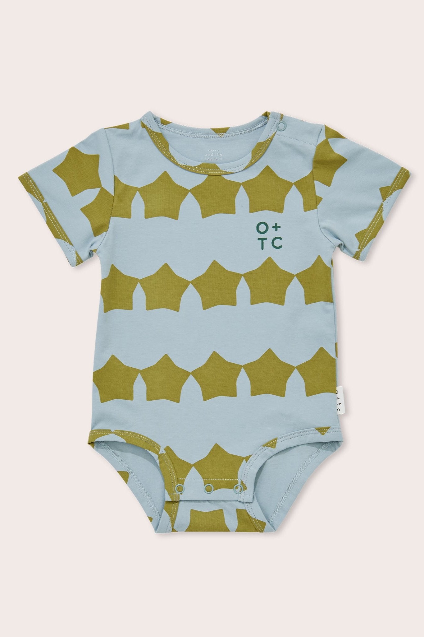 The Evergreen Supernova Bodysuit by OLIVE + THE CAPTAIN is a short-sleeved baby onesie adorned with a light blue background and patterned green geometric shapes. Crafted from premium cotton, it features a convenient snap closure at the bottom for easy dressing, as well as a small "O+TC" logo on the chest.