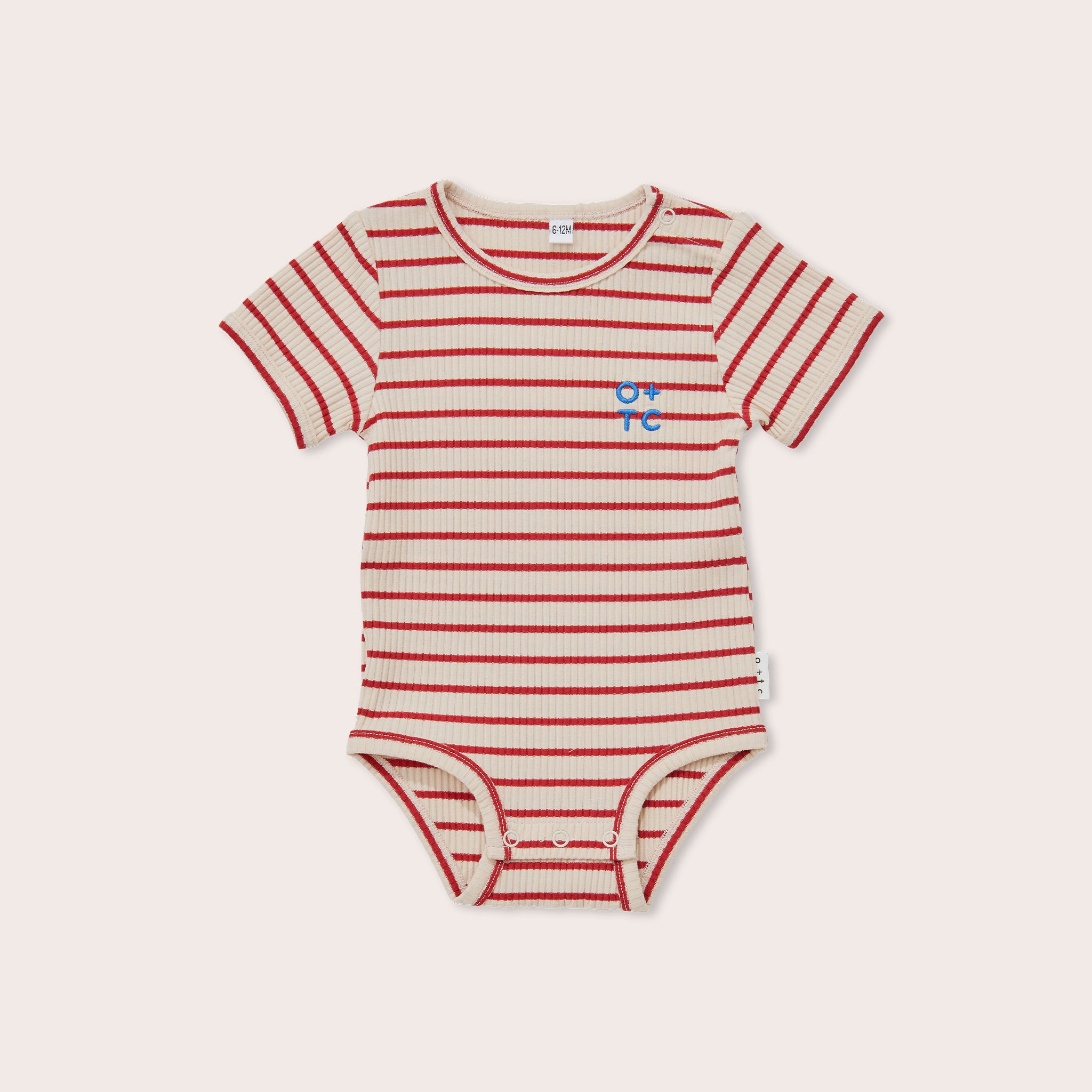 The Samba Stripe Bodysuit by OLIVE + THE CAPTAIN features a white short-sleeved design with horizontal red stripes and a small blue symbol on the left chest. The bodysuit is crafted from premium ribbed cotton fabric and includes snap closures at the bottom for easy diaper changes.