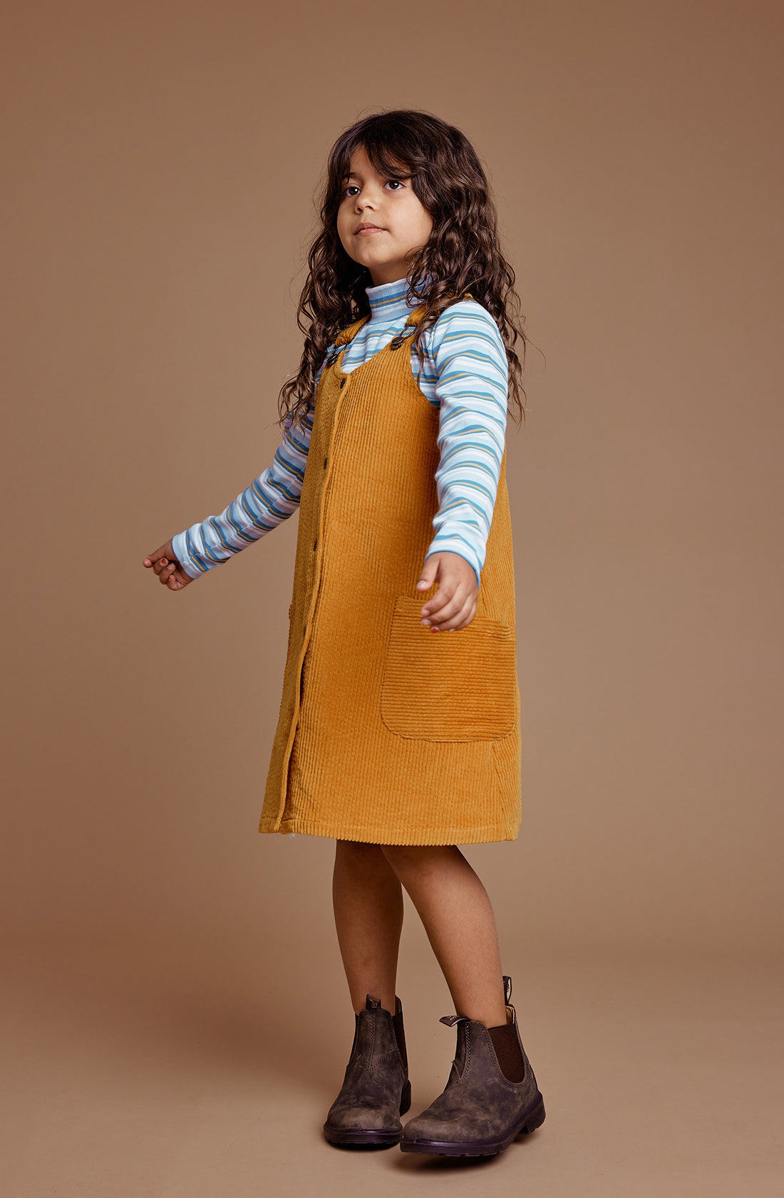 Young girl wearing the GOLDIE + ACE  Polly Corduroy Pinafore Dress in Golden.