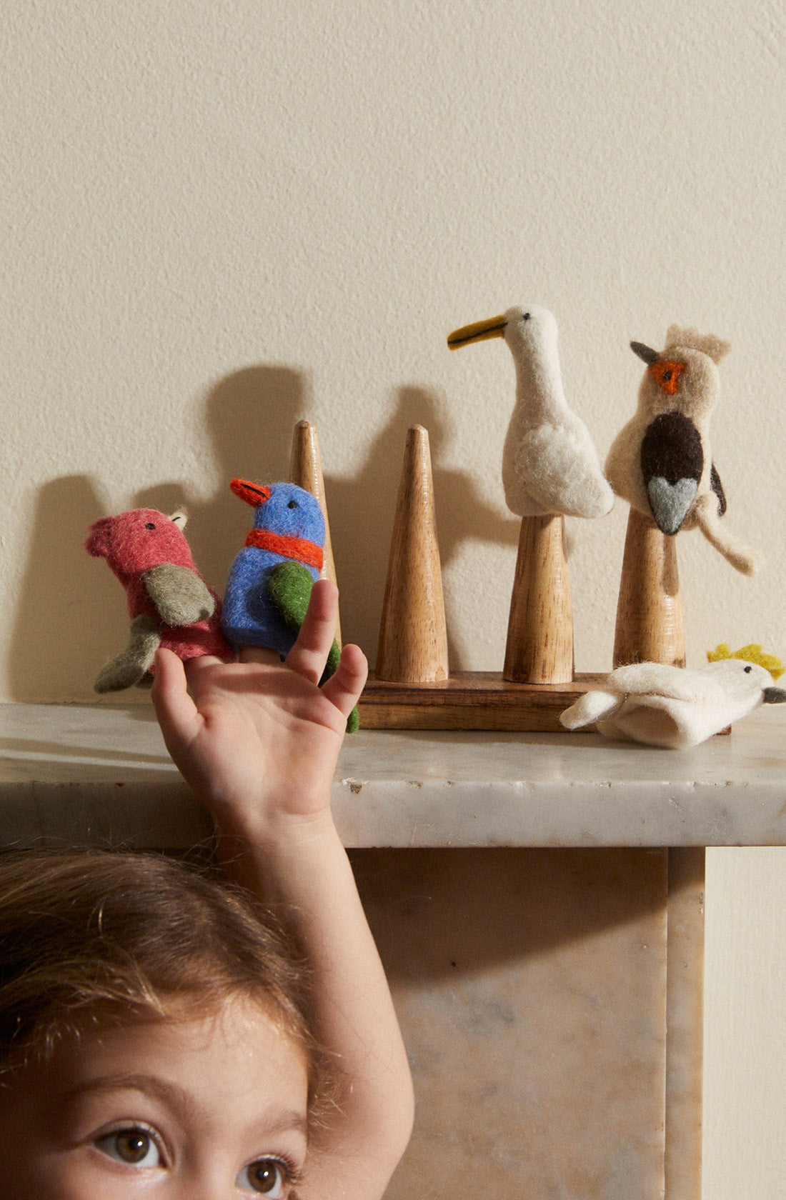 A kid with two of the australian bird finger puppets on her fingers.