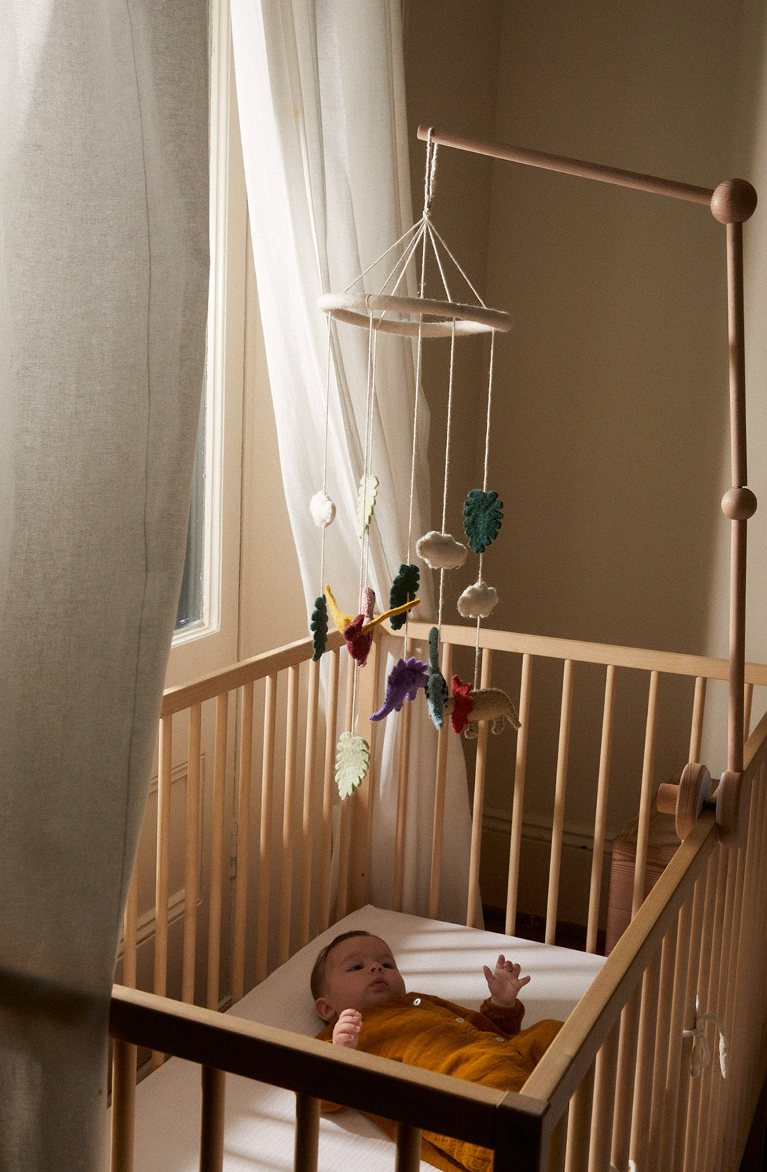 A baby lying in it cot with the PHILÉ baby mobile hanging above it.