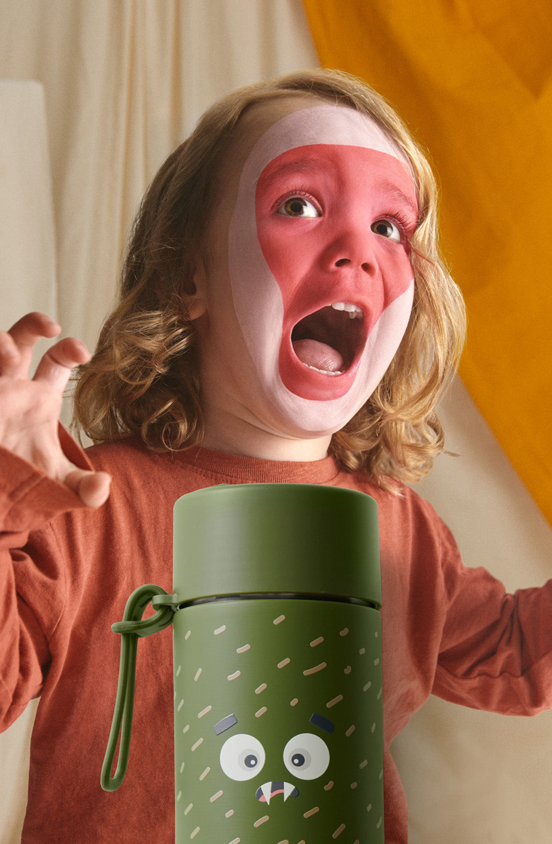 Child with pink face paint pulling a scary face with frankster Scout
