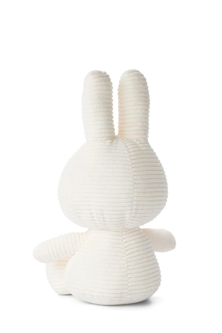 Displayed is an adorable plush gift from the back, showcasing a white ribbed texture. The toy, reminiscent of Miffy ECO Corduroy with its elongated ears and round body, is positioned against a plain white backdrop. It measures 33 cm and features recycled PET filling, contributing to its eco-friendly appeal. This charming design comes from the collaboration between BON TON TOYS and MIFFY.