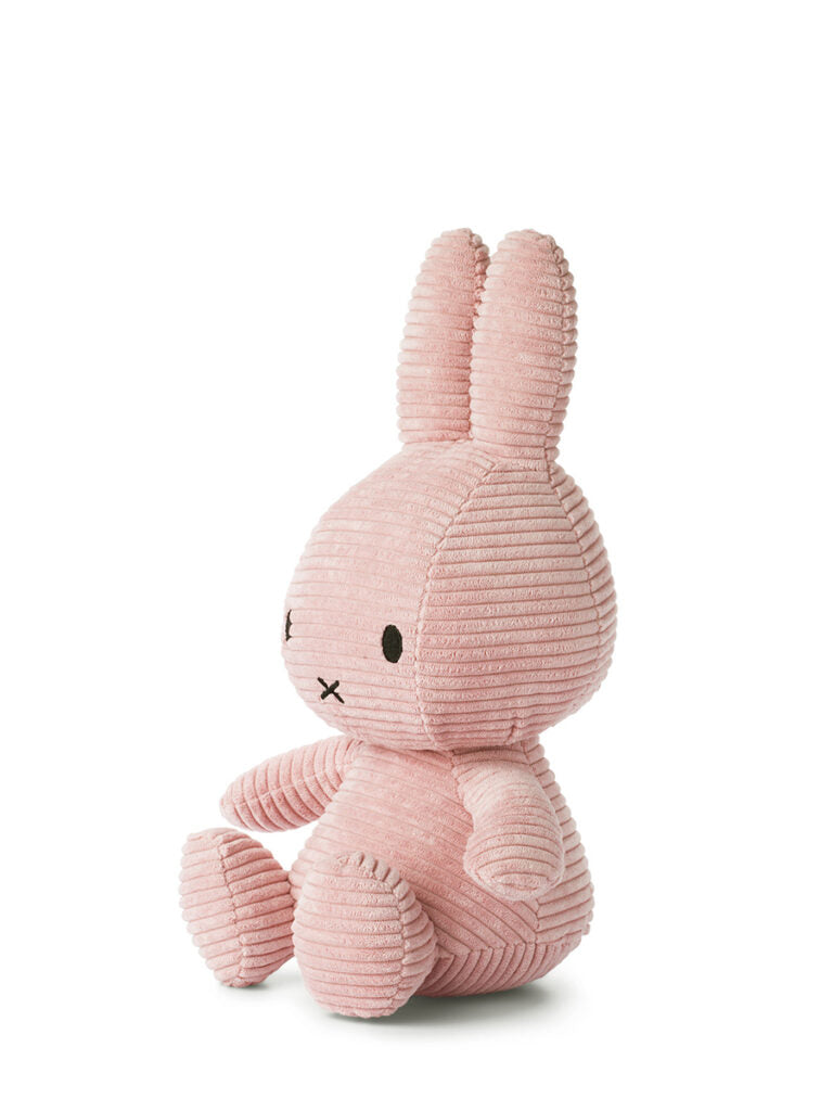 A Miffy ECO Corduroy Pink 33 cm plush toy from BON TON TOYS X MIFFY sits upright against a white background, facing slightly to the left. With its long ears and minimalistic facial details, this corduroy bunny is an ideal gift for any occasion.