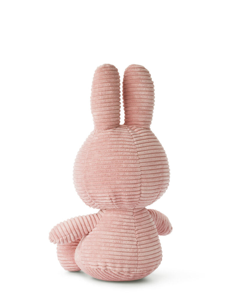 A plush toy, named Miffy ECO Corduroy Pink 33 cm, crafted by BON TON TOYS X MIFFY, features a charming bunny with long ears sitting and facing away. It is made of light pink ribbed corduroy fabric and is set against a plain white background.