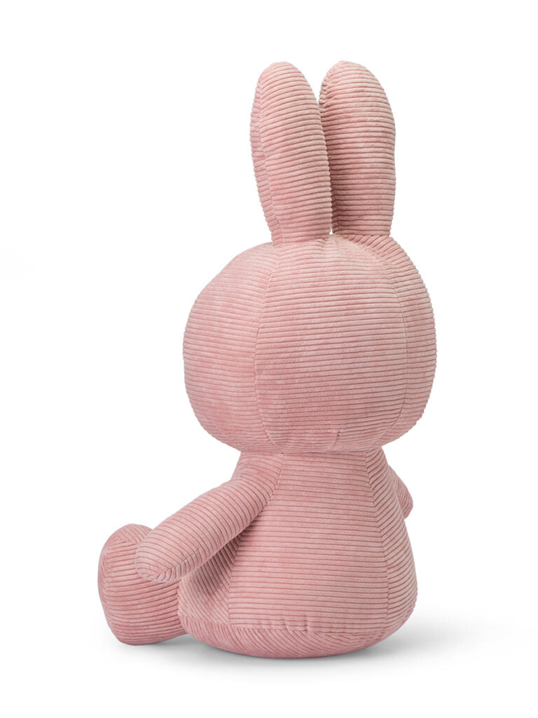 A plush gift for any occasion, the Miffy Sitting Corduroy Pink 70 cm from BON TON TOYS X MIFFY is crafted from soft pink corduroy fabric. Sitting with its back facing the viewer, it features long ears and a round shape, highlighting its cuddly texture and simple design.