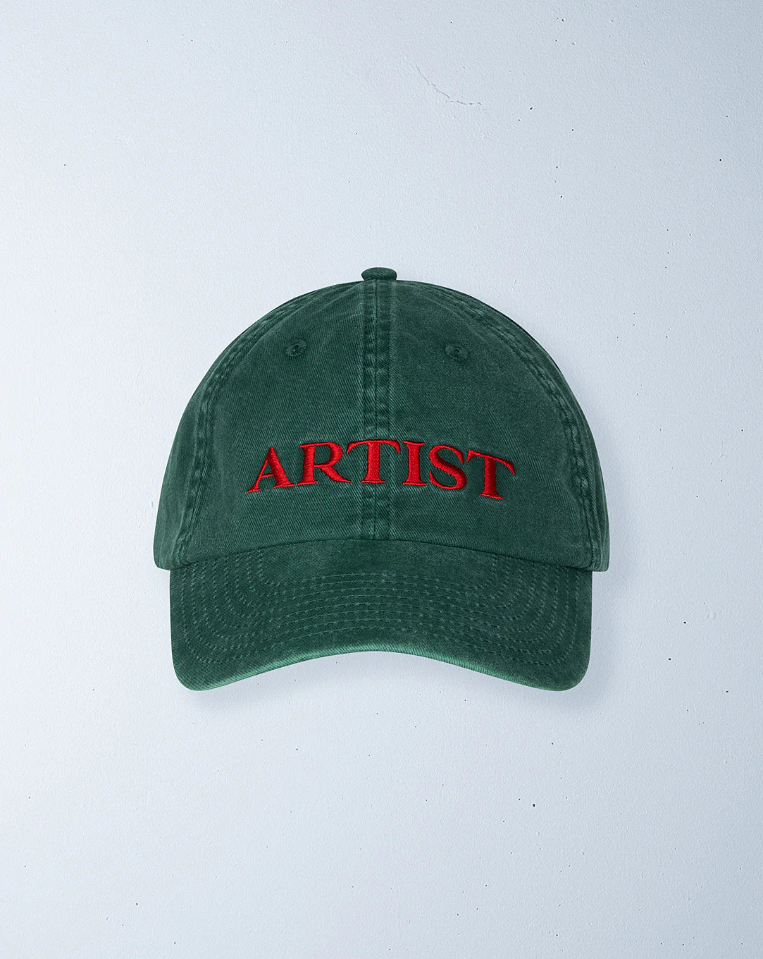 The Ziggy Zaza ~ Artist Cap in Forest Green by ZIGGY ZAZA is made from pre-washed cotton canvas, features "ARTIST" embroidered in red on the front, and has an adjustable brass clasp. It's set against a light gray background.