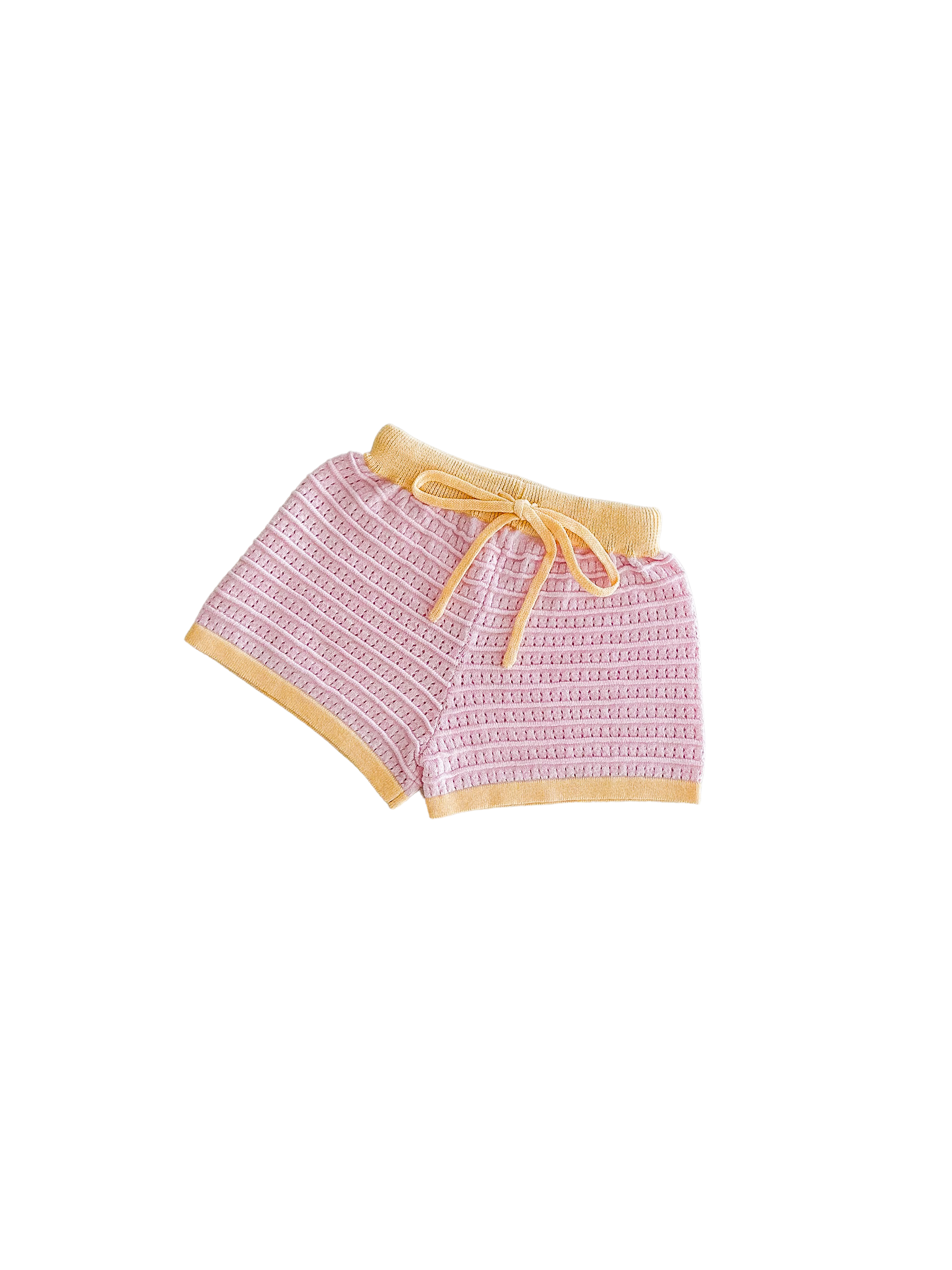 These Shorts Clementine from ZIGGY LOU's Summer Collection showcase a delightful textured pattern in pink crochet, accented with a vibrant yellow waistband and hem. Made entirely from 100% cotton, they include a practical yellow drawstring contrasting against a bold black background.