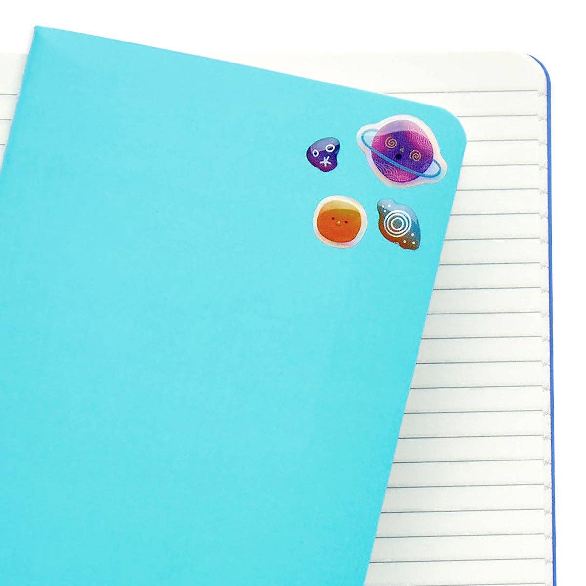 A bunch of OOLY stickiville planet pals stickers on a blue cover notebook.