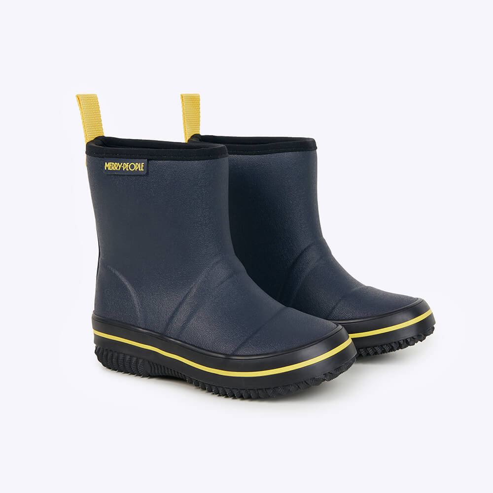 The Merry People Andie Kids Gumboot in Midnight Blue is a vegan, waterproof boot featuring yellow accents on the soles and loops. It has a textured sole for grip and displays the MERRY PEOPLE logo on the side, set against a plain white background.