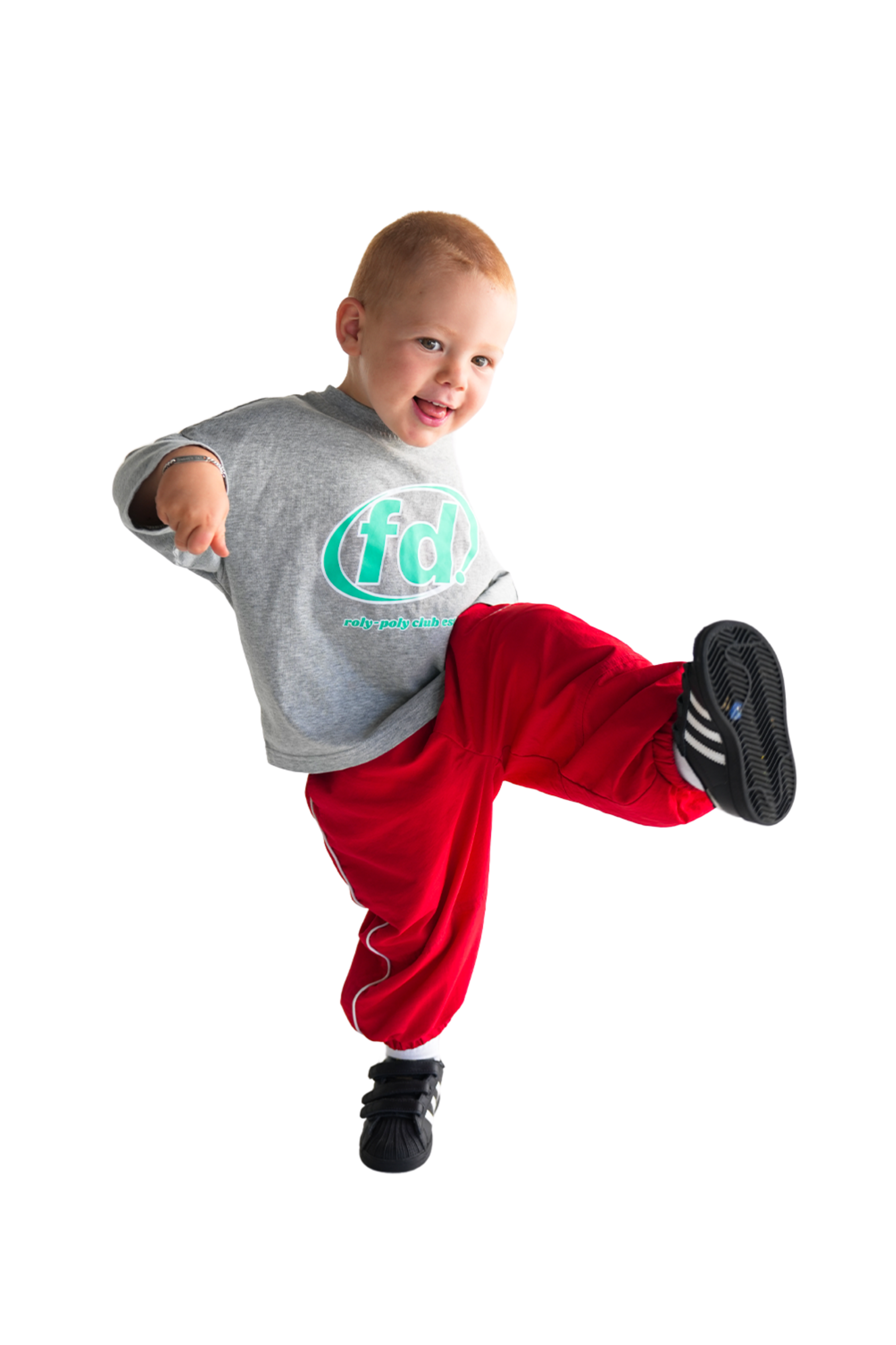 A young child performs a playful kick, smiling widely in Franco's Dad ~ Long Sleeve Tee Grey Marle and red pants. The buttery soft stretch cotton shirt by FRANCO'S DAD complements the child's dance-like pose against the white background, exuding comfort and joy.