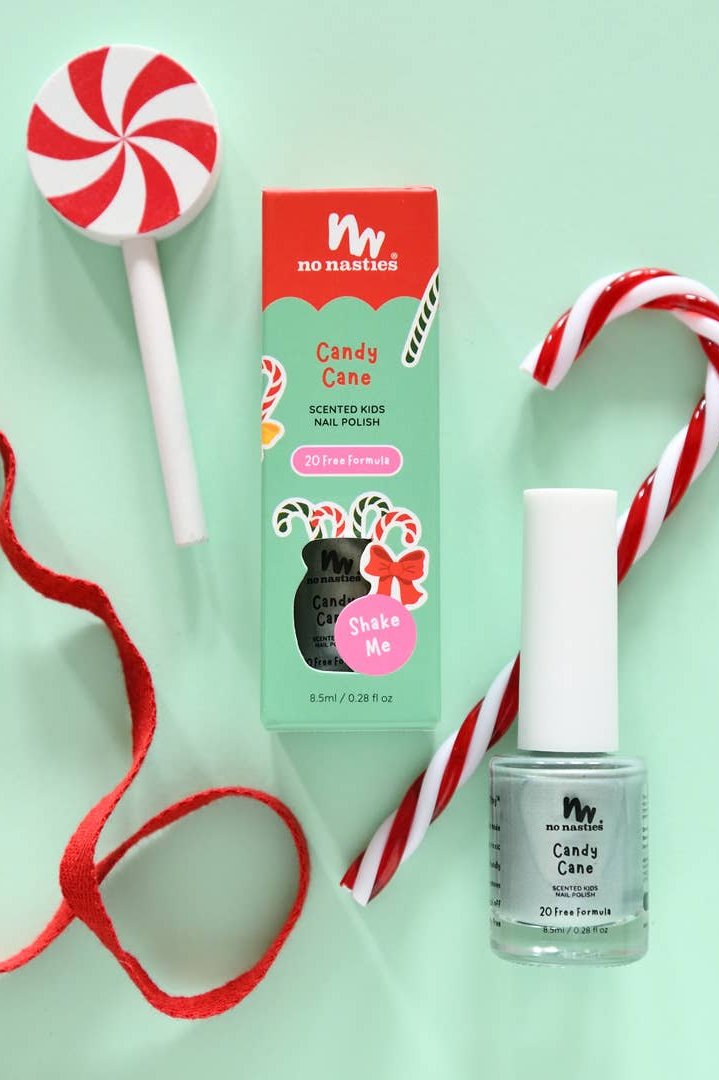 A bottle of "Candy Cane" Water Based Scented Scratch Off Kids Nail Polish by NO NASTIES, which is non-toxic and cruelty-free, is displayed in its packaging with a candy cane and a peppermint swirl lollipop, all on a mint green background.