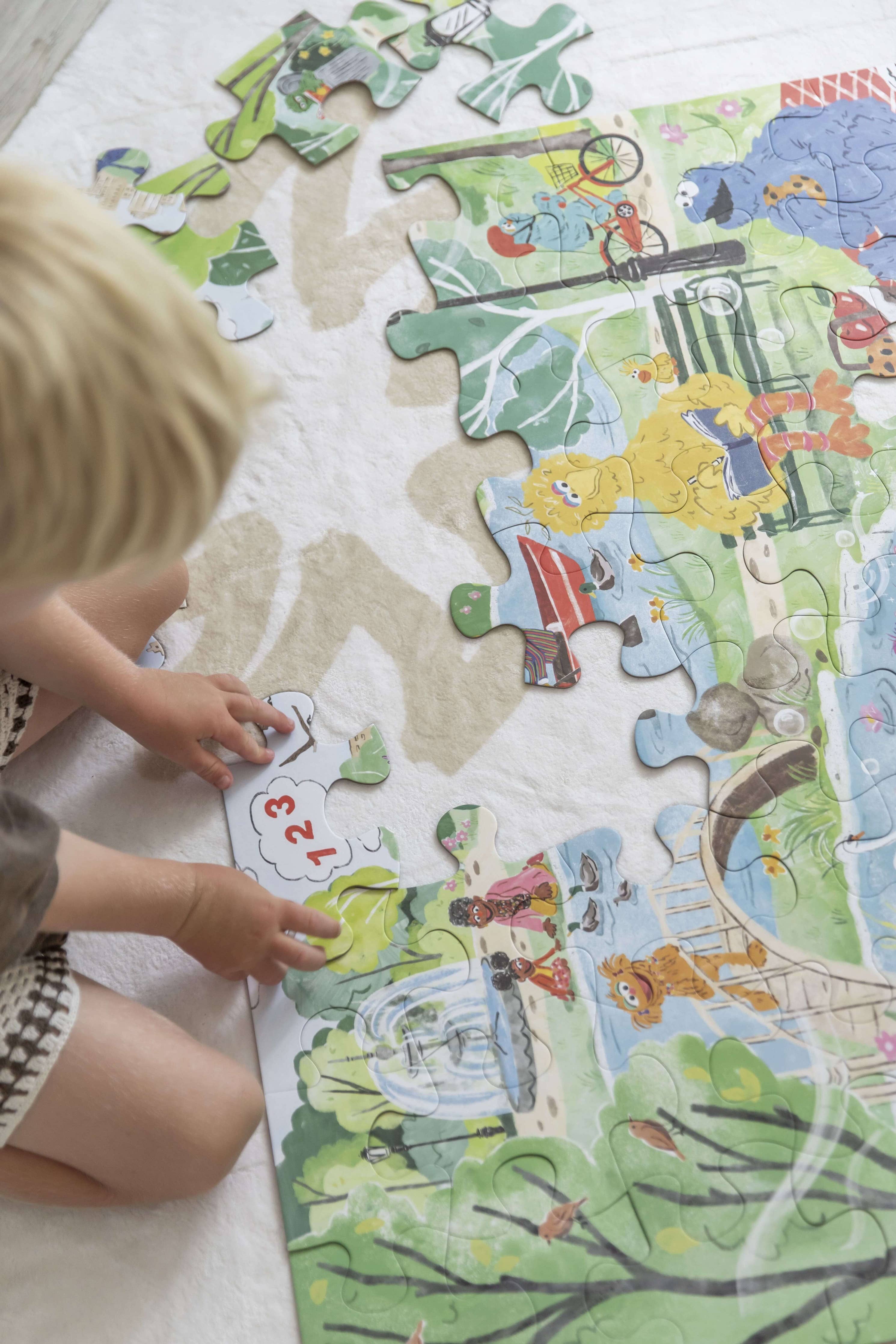 A young boy putting a puzzle piece in the sesame street puzzle.