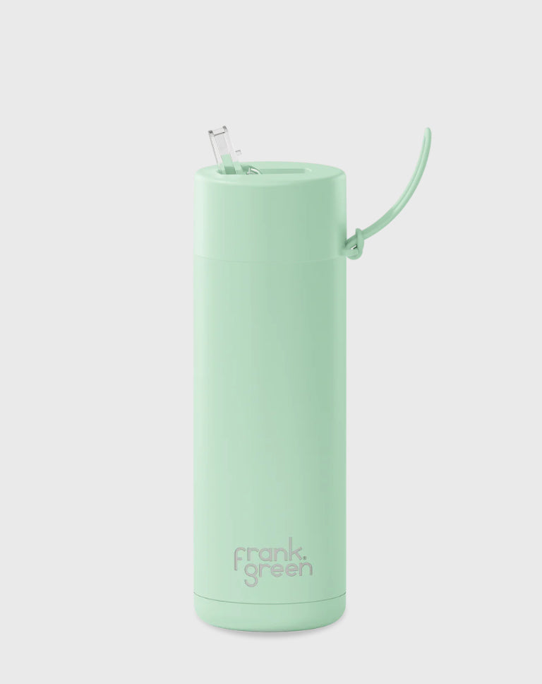 A mint green reusable travel cup with a lid and retractable straw. Made with stainless steel construction, this Frank Green Ceramic Reusable Bottle (595ml - 20oz Straw Lid - Mint Gelato) features a handle attached to the lid and displays the brand name "FRANK GREEN" in gray letters near the bottom. The background is a plain light gray.