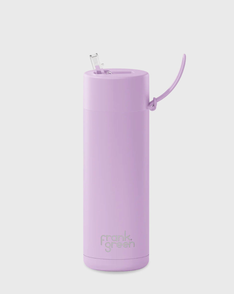 The FRANK GREEN Ceramic Reusable Bottle 595ml 20oz in Lilac Haze is a sleek, tall reusable bottle featuring a pastel purple color. It comes with a flip-top lid and metal straw, with the brand name "FRANK GREEN" embossed near the base. This BPA-free bottle boasts a modern minimalist design and triple-wall vacuum insulation for maximum temperature retention.