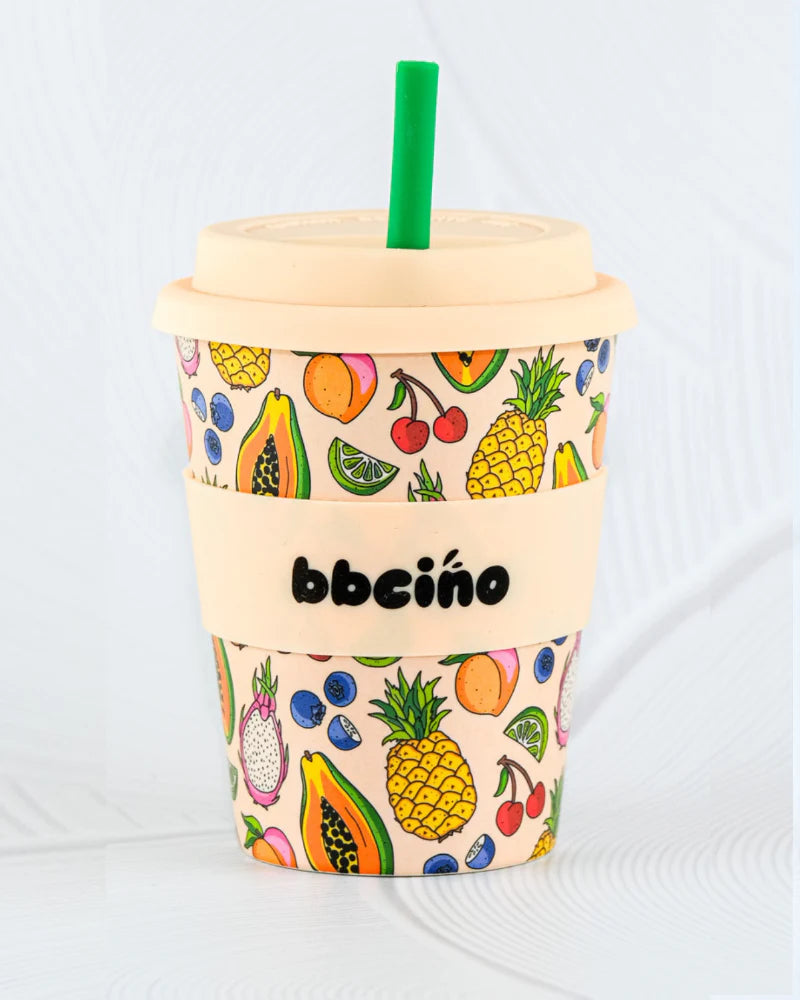 Introducing the Reusable BiggieCino Cup 350ml Troppo (Limited Edition) from BBCINO. This eco-friendly cup is crafted from sustainable bamboo fibers and comes with a beige lid and a green straw. It showcases vibrant illustrations of tropical fruits like pineapples, papayas, and cherries. The sleeve features the text "BBCINO" on a light gray background.