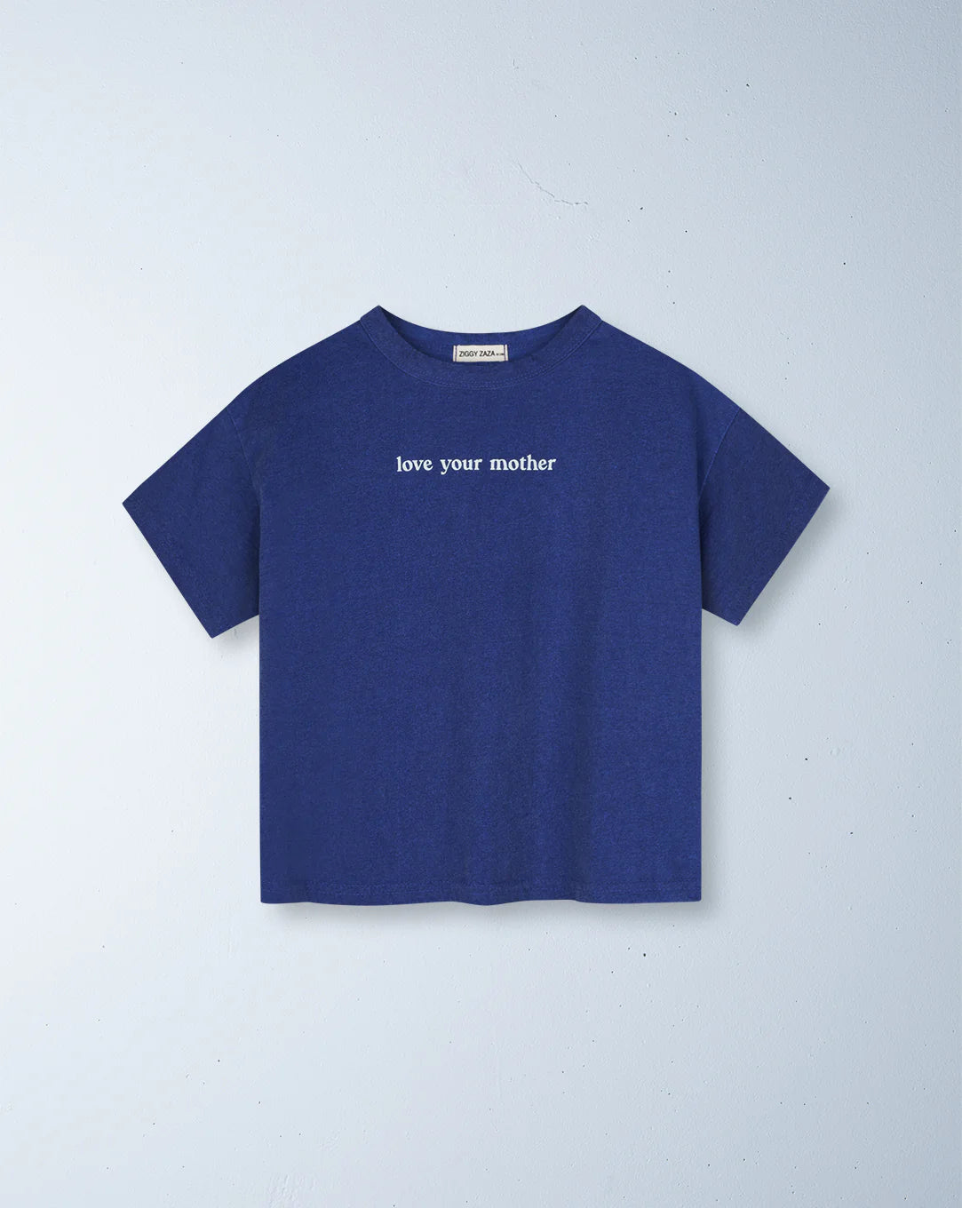 The Ziggy Zaza "Love Your Mother Tee" in Lapis Blue, size 7-9, by ZIGGY ZAZA features a relaxed boxy fit with short sleeves. Made from premium lightweight washed cotton, it sports "love your mother" in small white font on the front and is shown against a light grey background.