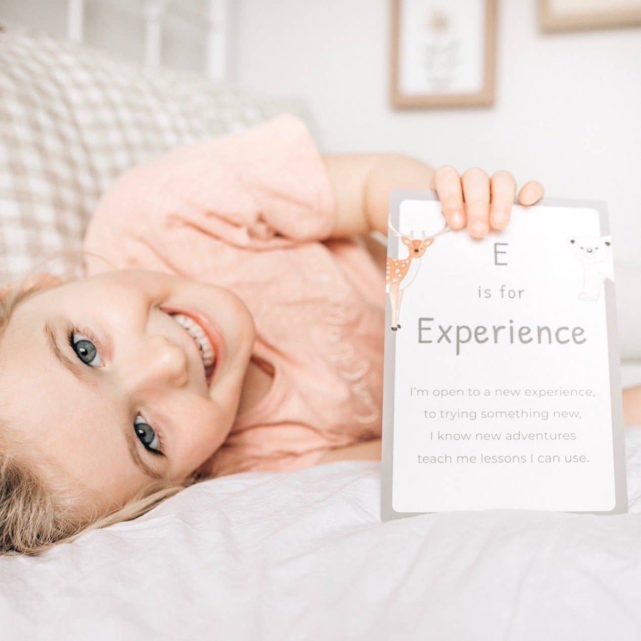 A young girl holding the E letter mindful affirmation card.