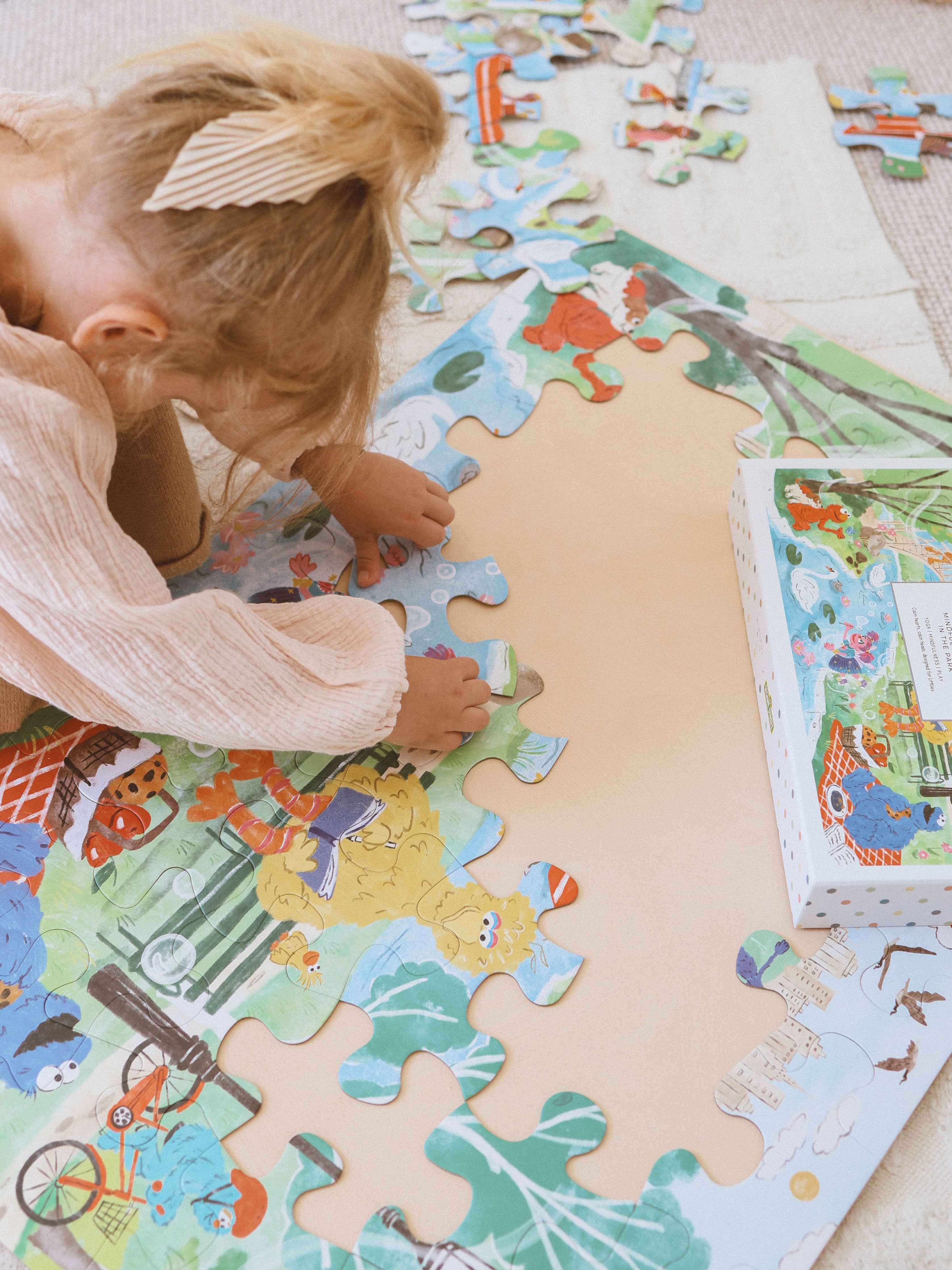 A young girl putting a puzzle piece in the sesame street puzzle.