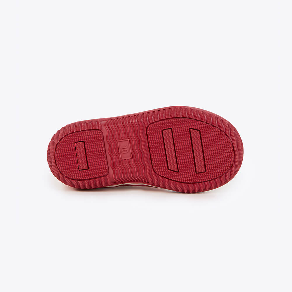 The Merry People Andie Kids Gumboot in Bubblegum features a red shoe sole with a textured tread pattern, including wavy lines and rectangular indents, providing excellent grip. Designed for kids, it offers exceptional arch support while keeping their feet stylish and playful.