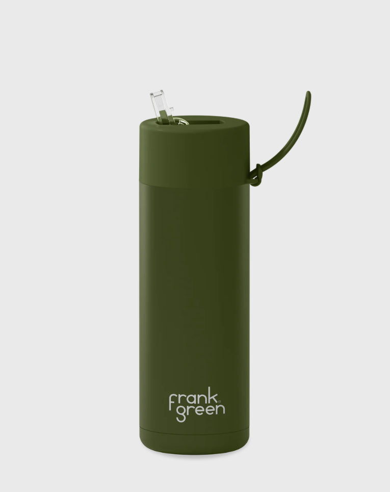 Introducing the Frank Green Ceramic Reusable Bottle, featuring a khaki color and a 595ml (20oz) capacity. This vacuum insulated bottle has a cylindrical shape, complete with a convenient flip-up straw and a handle attached to the lid. The bottom of the bottle is prominently labeled with "FRANK GREEN" in white letters against its plain white background.