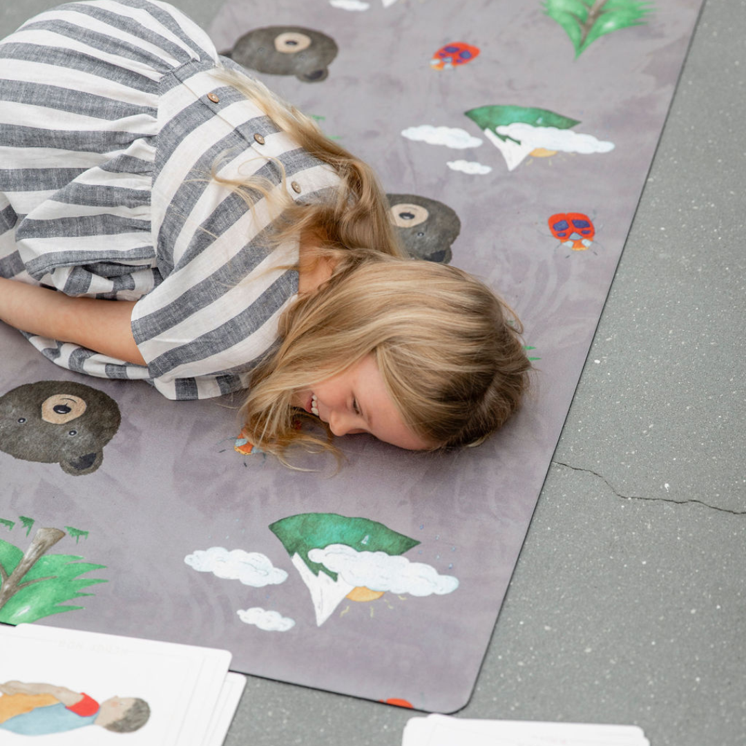 A young girl lying on the nature kids yoga mat.