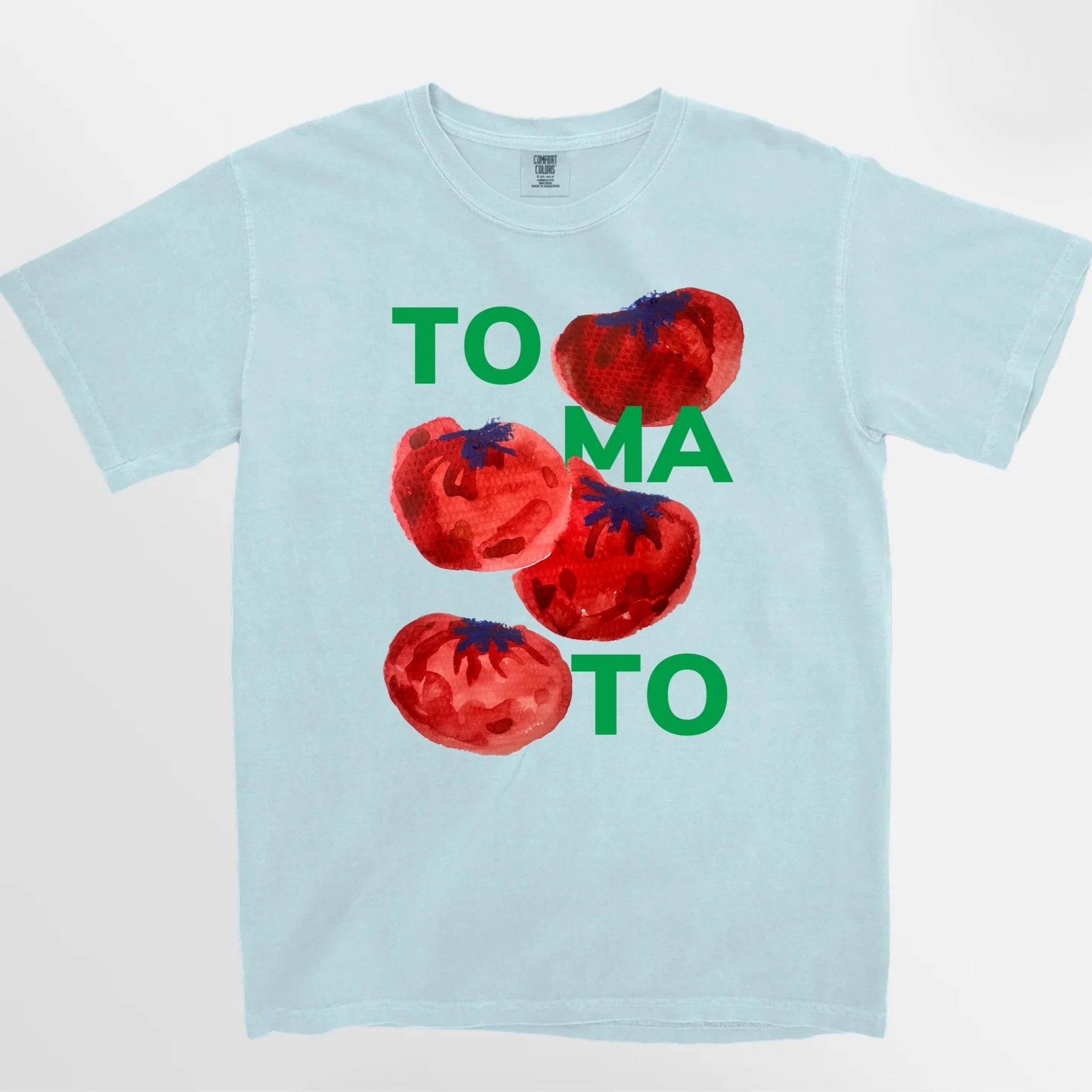 The Tomato T-Shirt by MAKU THE LABEL is a light blue unisex tee with four red, watercolor tomatoes and green "TO MA TO" text, featuring a classic fit and hand-painted design.