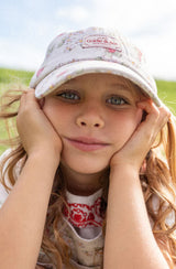 A young girl wearing the GOLDIE + ACE  Strawberry Fields Tate Cap.