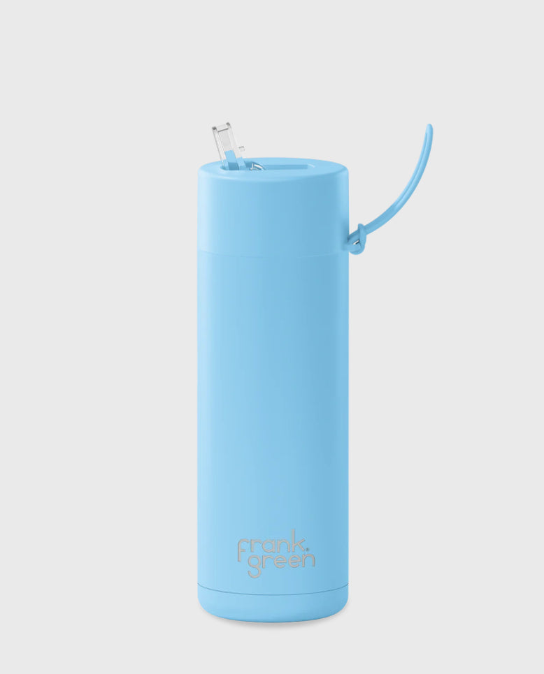 A tall, cylindrical, sky blue ceramic reusable bottle with a straw lid from FRANK GREEN. The bottle has a sleek, smooth design with "frank green" written in small gray letters near the bottom. This Frank Green Ceramic Reusable Bottle has a capacity of 595ml / 20oz.