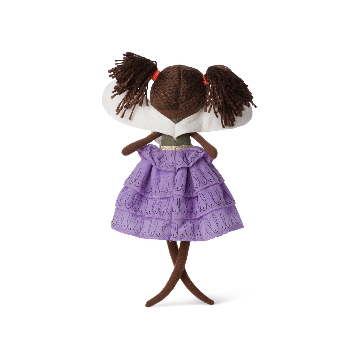 The Fairy Feline 35cm from the PICCA LOULOU collection features a fabric doll with brown yarn hair styled in pigtails adorned with red bands, viewed from the back. She is dressed in a lavender ruffled dress with intricate patterns, a white collar, and a green belt. Her legs are posed in a slight cross stance.