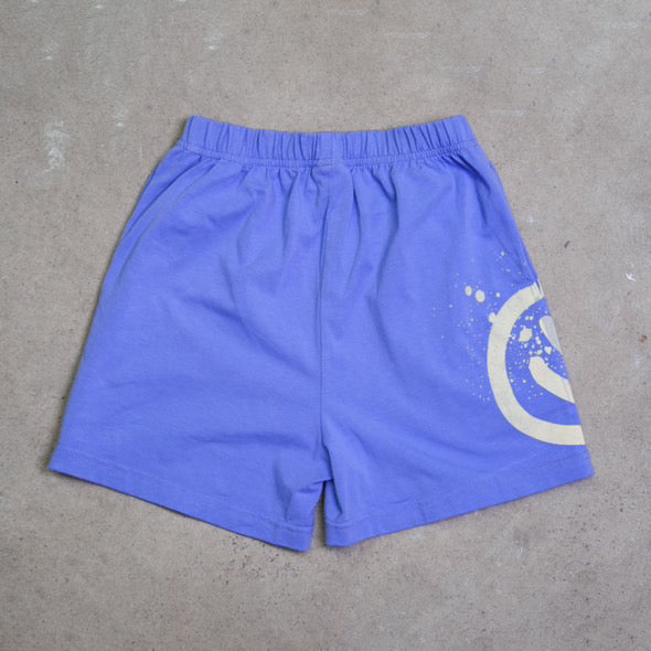 Blue acid dye shorts with an elastic waistband from FRANCO'S DAD, showcasing a white splatter design and a partial circle emblem on the right leg. Made from stretch cotton, they are laid flat on a neutral gray surface.