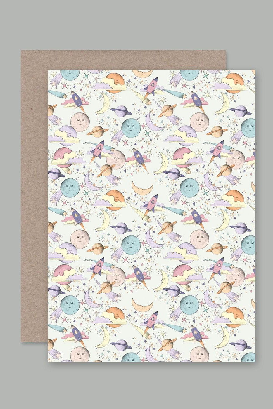 The "Moons & Planets" Greeting Card by AHD PAPER CO presents a whimsical space theme featuring rockets, moons, planets, stars, and clouds in pastel colors. Made in Australia from recycled paper, this blank greeting card is accompanied by a brown envelope and set against a gray background.