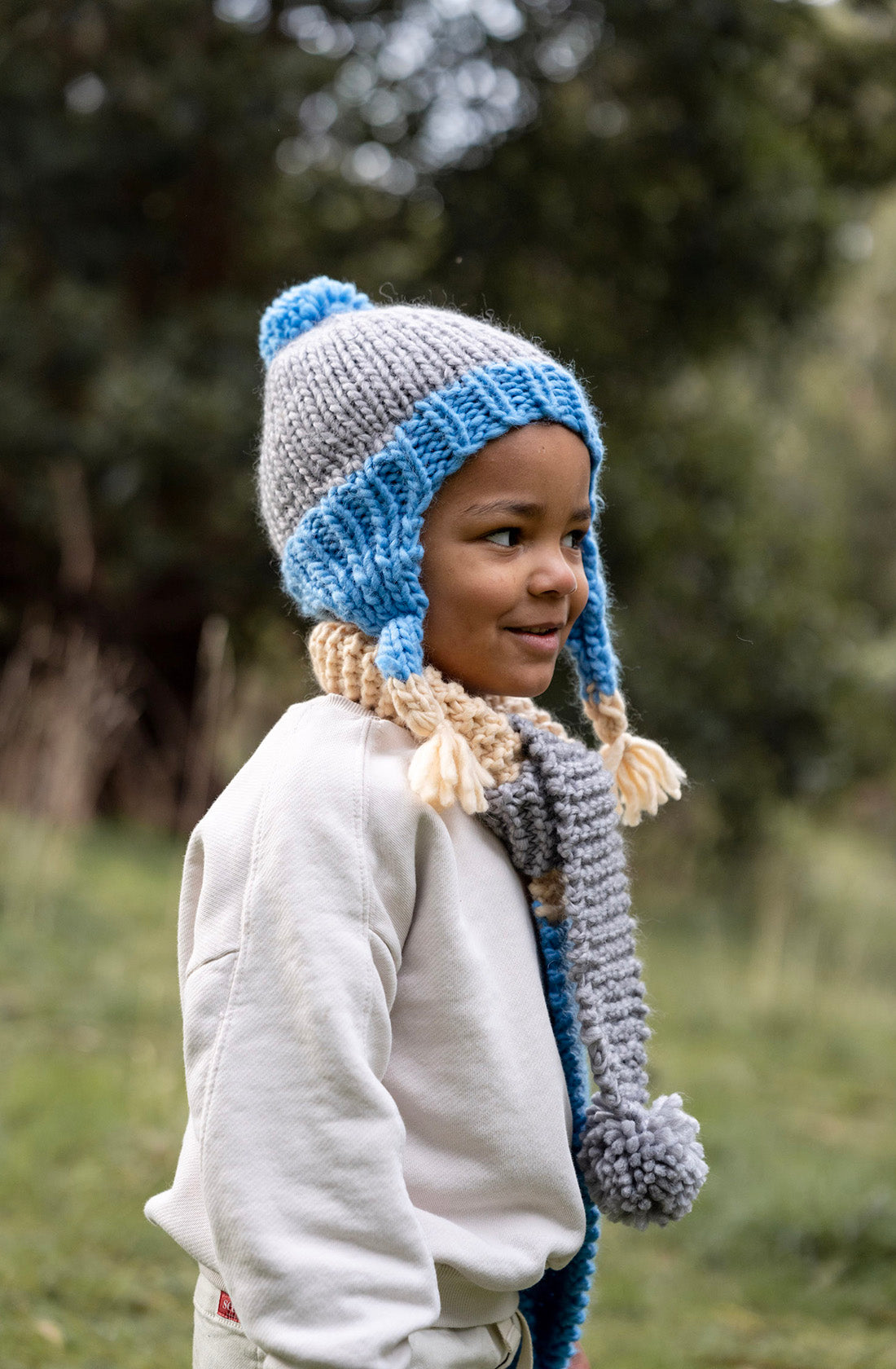 A young boy outside wearing the earth scarf ocean by Acorn Kids.