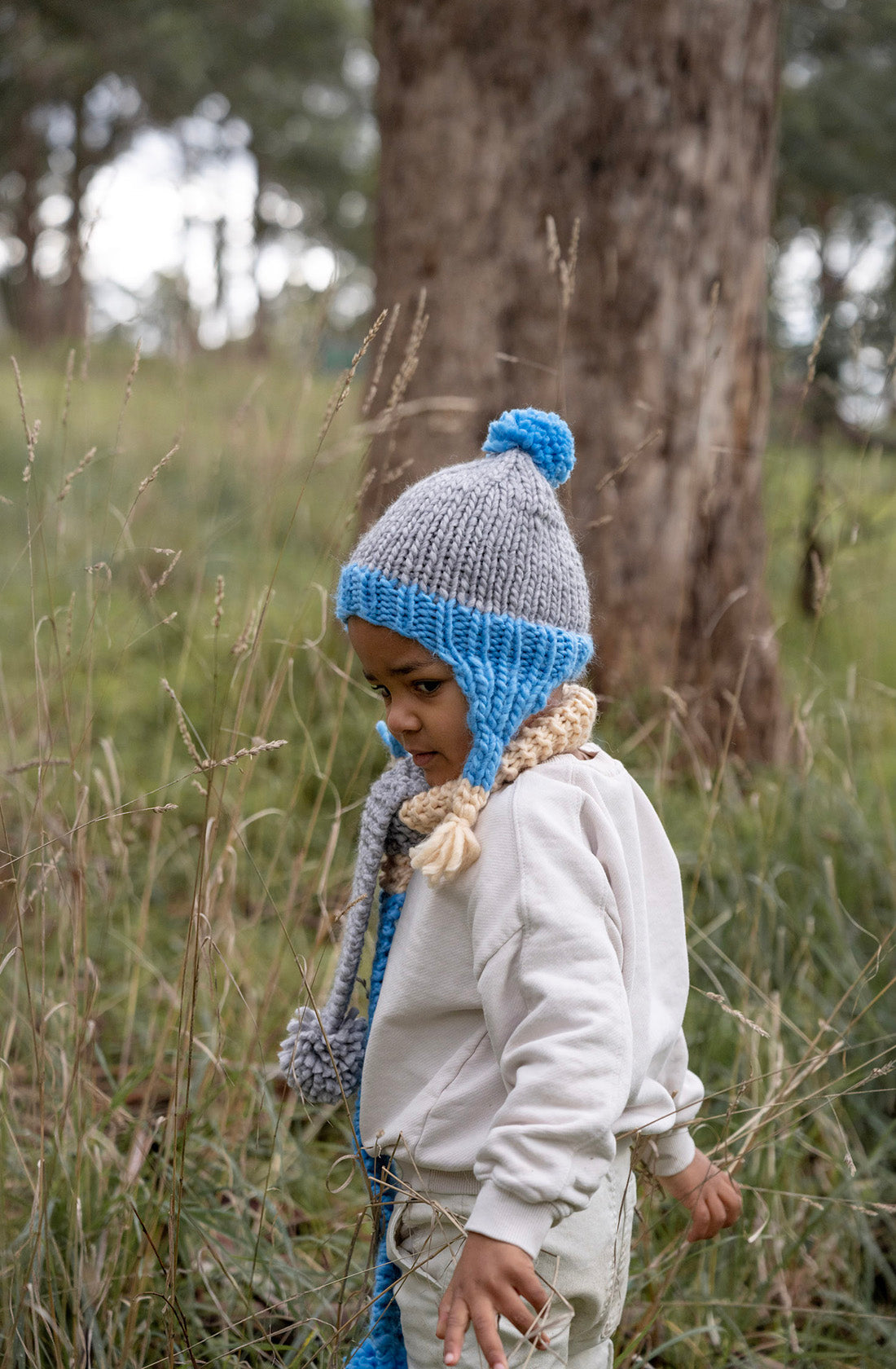 Boy wearing blue acorn kids beanie and wandering the forest.