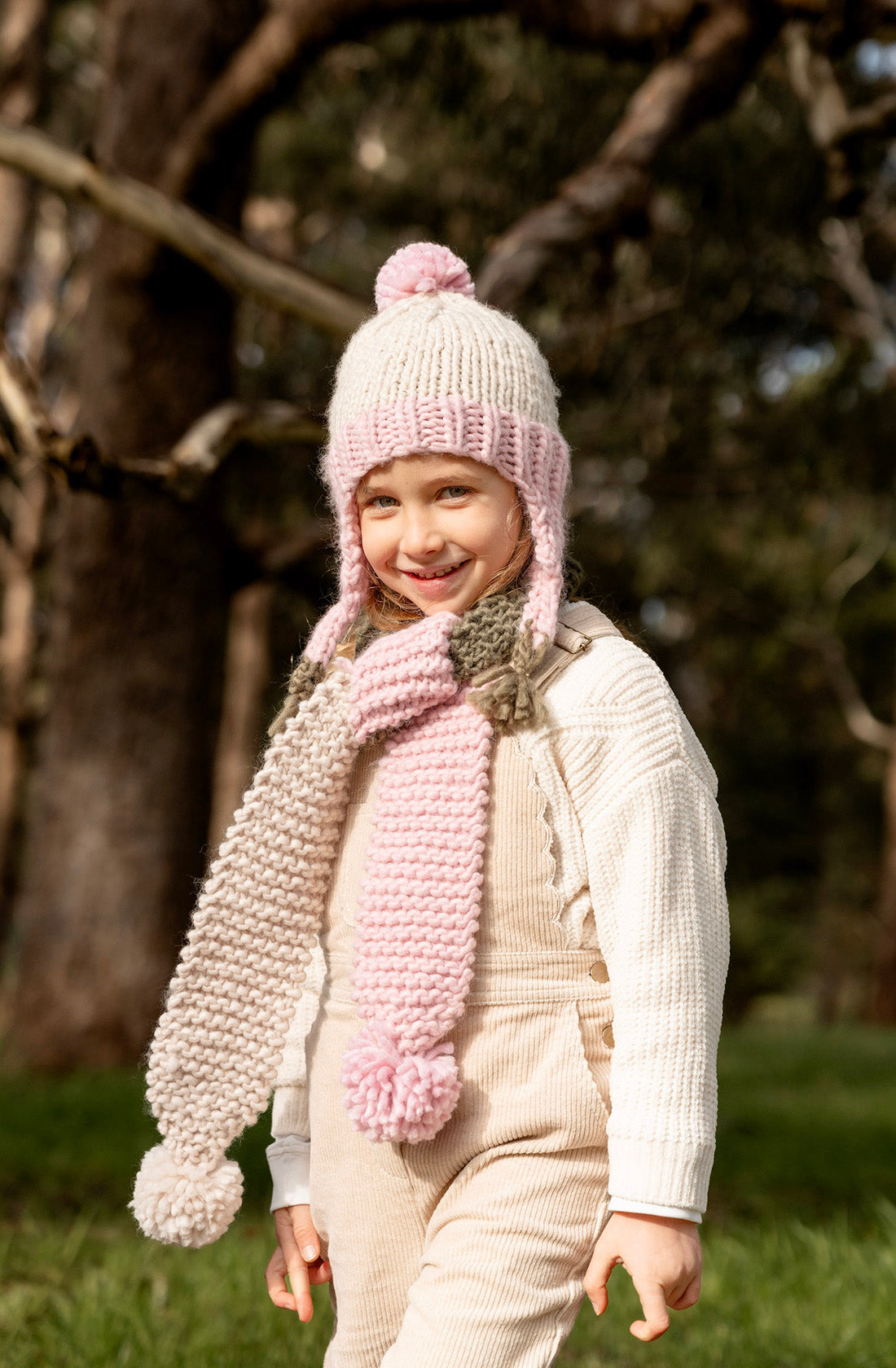 A young girl outside wearing the earth scarf blossom by Acorn Kids outside in a field.