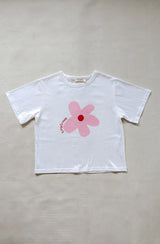 Flat lay of white t-shirt with pink/red flower print on grey background