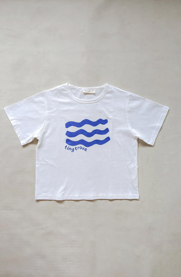 Flat lay of white t-shirt with blue wave print on a grey background