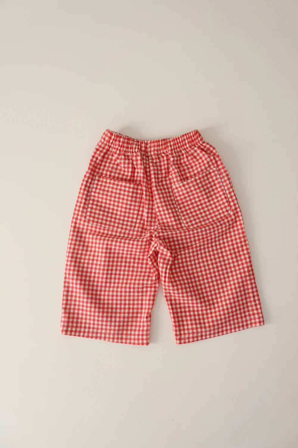 The WORN CURATIONS All Day Pant Chilli is a unisex children’s gingham pant with a comfy elastic waistband in red and white checks, shown laid flat on a light background.