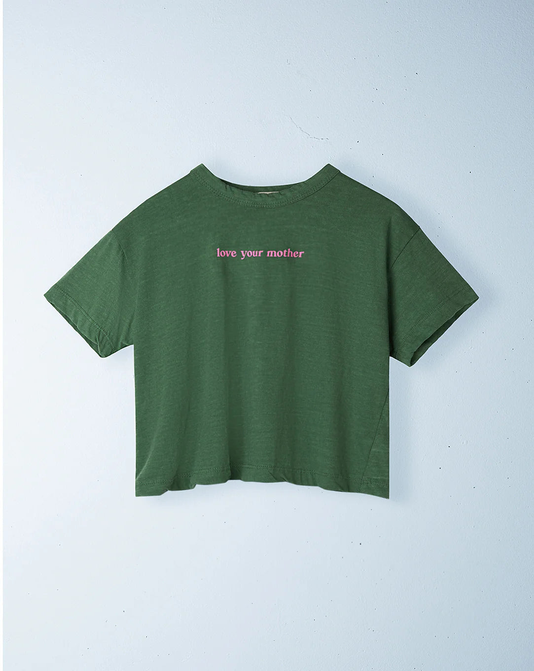 The Ziggy Zaza ~ Love Your Mother Tee Lizard by ZIGGY ZAZA is a green cropped T-shirt in lightweight washed cotton. It features "love your mother" in small pink letters and has a relaxed boxy fit, displayed against a light background for a fresh, modern look.